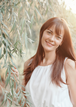 Woman smiling outdoors with nature, portraying biomimetic dentistry