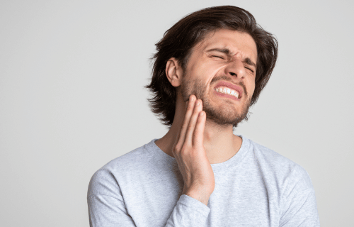 Man holding his lower jaw portraying nerve damage after tooth extraaction